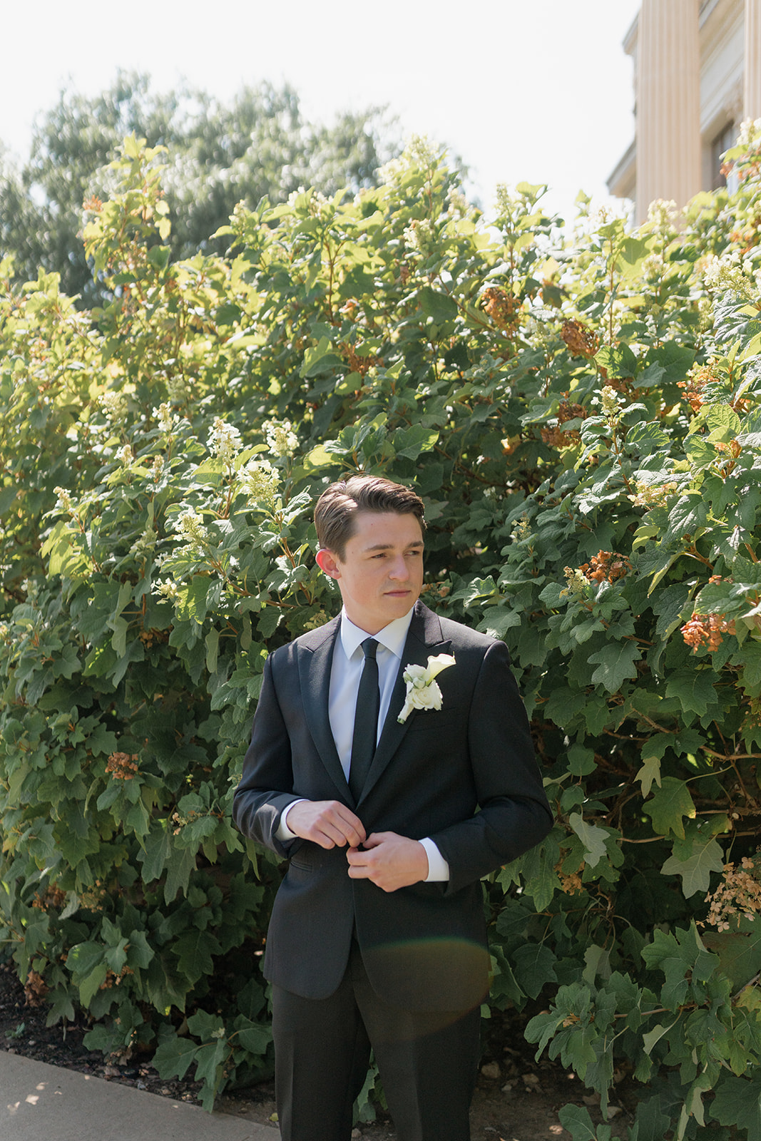 Groom buttoning his suit jacket outdoors before his Oklahoma City wedding ceremony at the Oklahoma Hall of Fame
