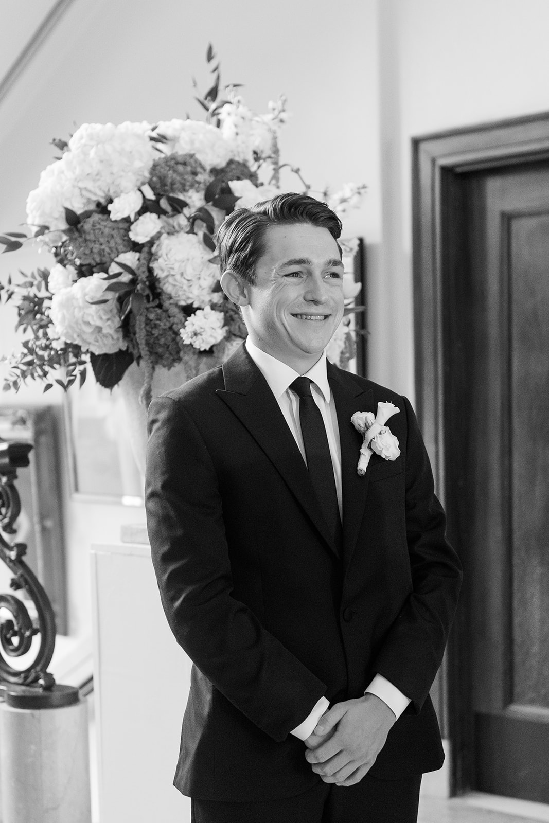 Black and white photo of the groom smiling at the altar during the wedding ceremony at the Oklahoma Hall of Fame, Oklahoma City