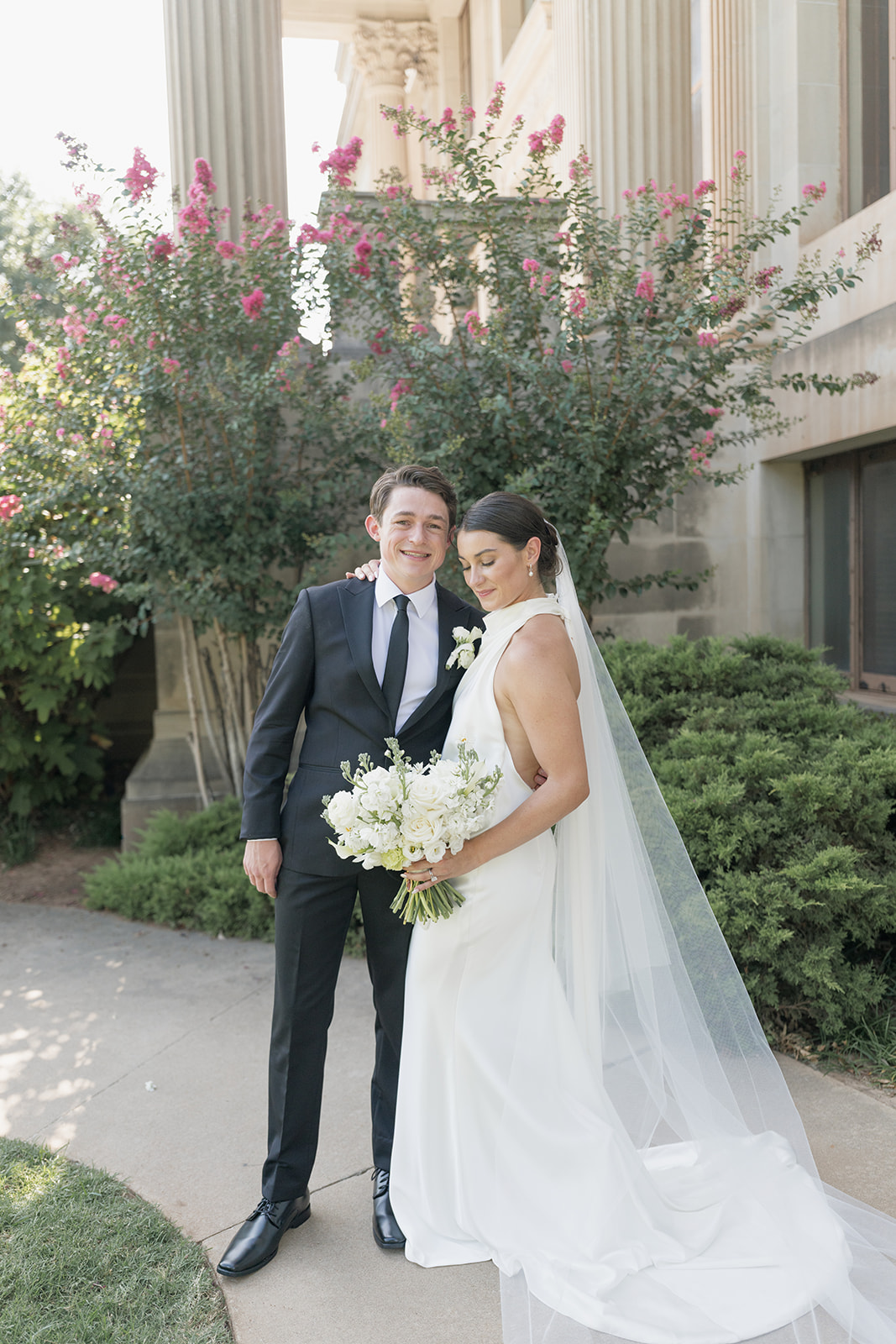 Newlywed portrait beside pink crepe myrtles at the Oklahoma Hall of Fame, Oklahoma City wedding photography