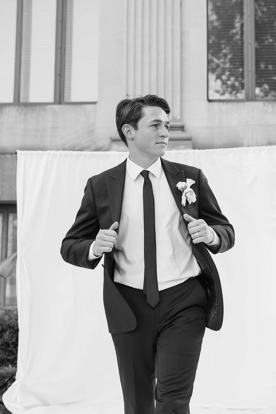 Black and white editorial groom portrait with a white backdrop at the Oklahoma Hall of Fame wedding in Oklahoma City